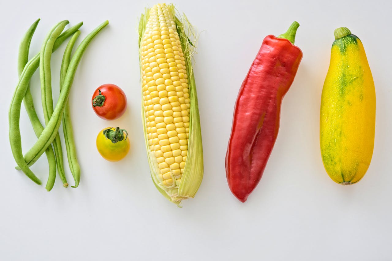 services-01 A vibrant assortment of fresh vegetables including corn, peppers, beans, and tomatoes.