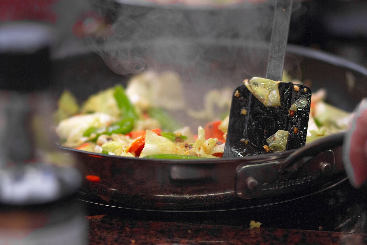 services-03 A vibrant stir fry of fresh vegetables sizzling in a pan, releasing steam.