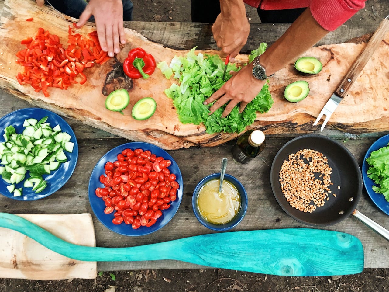 services-01 Fresh ingredients being prepared on a rustic wooden table, showcasing vibrant vegetables and hands at work.